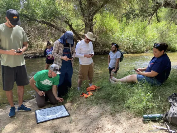 People standing on edge of river collecting data