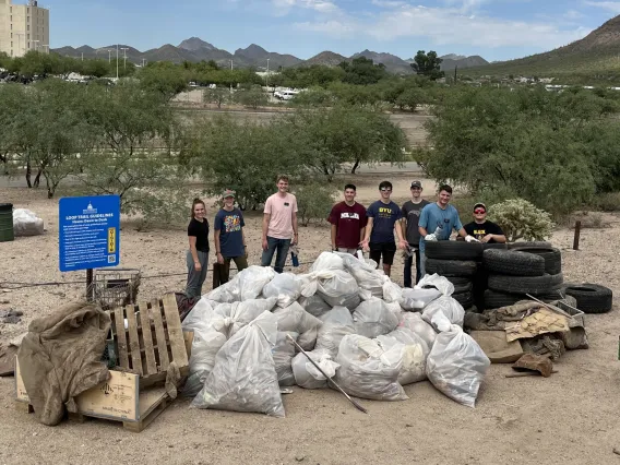 Group of people standing near trash collected in the Santa Cruz River