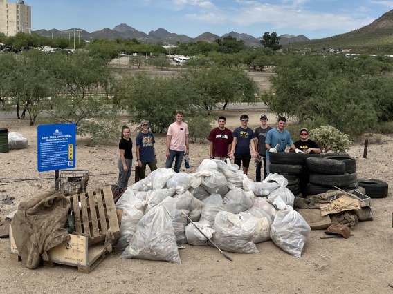 Group of people standing near trash collected in the Santa Cruz River