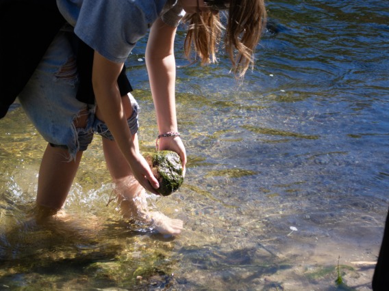 Student holding a rock above the Santa Cruz River
