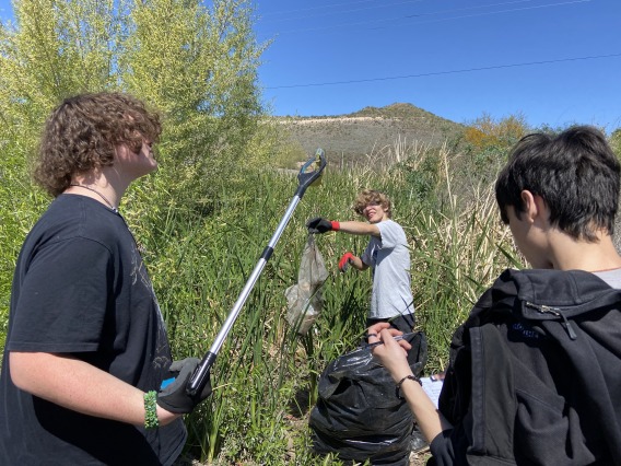 Students collecting trash in tall cattails on Santa Cruz River in Tucson