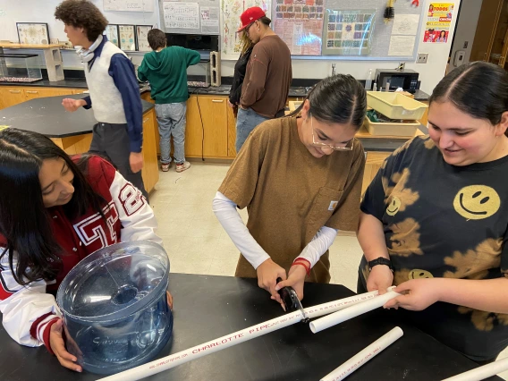 3 students cutting a PVC pipe