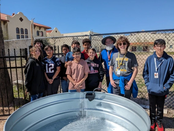 Middle school students standing around an empty metal tank