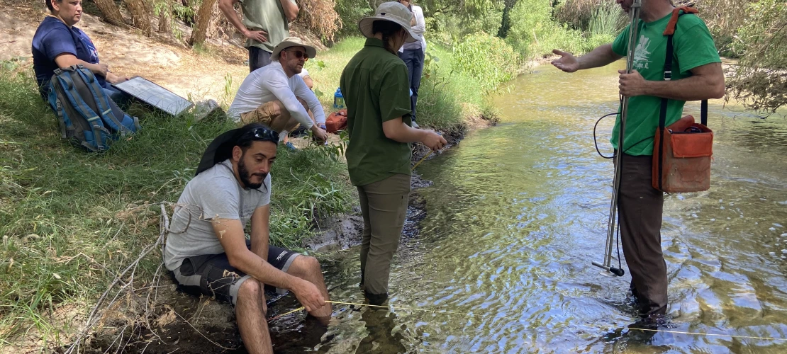 People standing in river holding measuring equipment