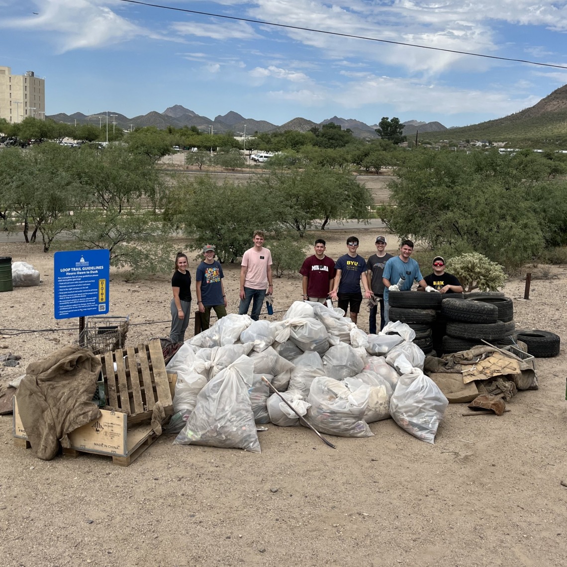 Group of people standing near trash collected in the Santa Cruz River