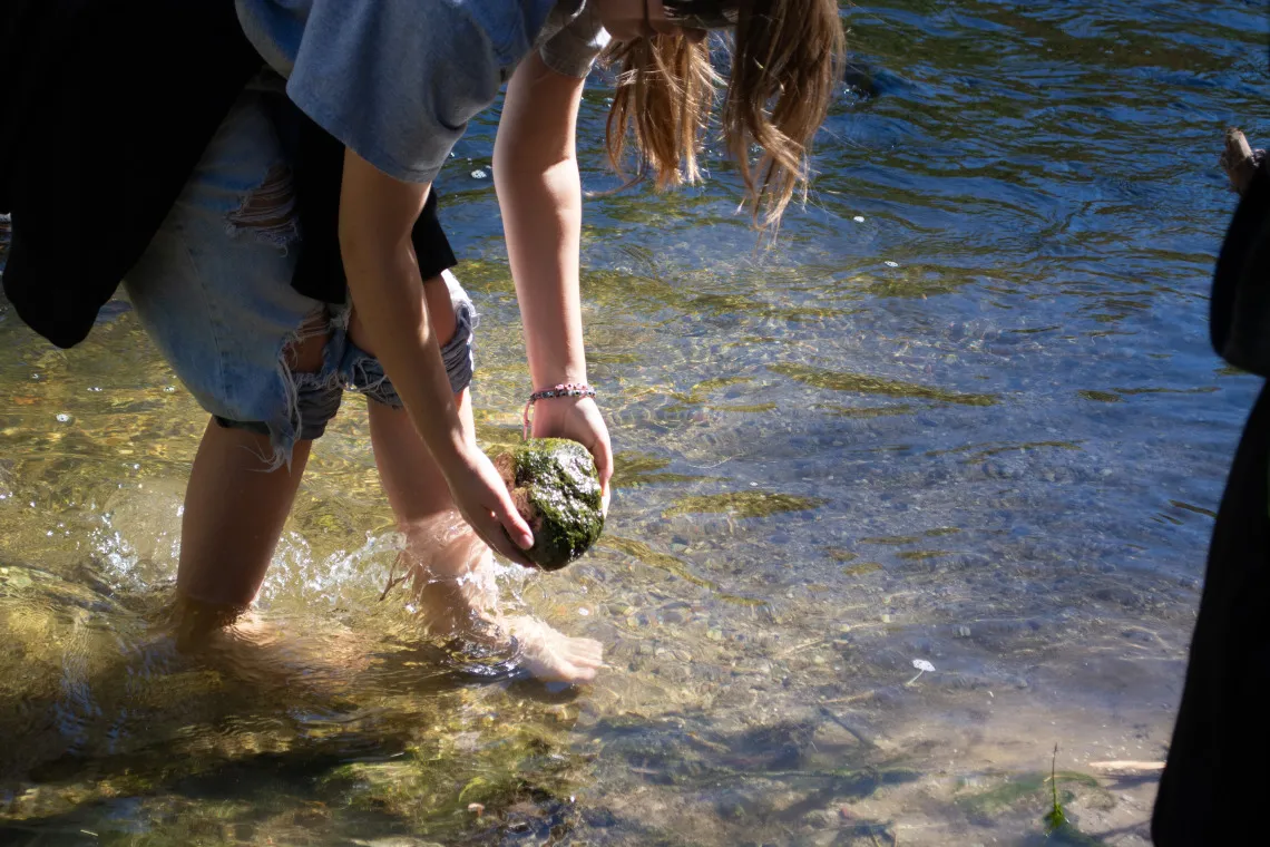 Student holding a rock above the Santa Cruz River