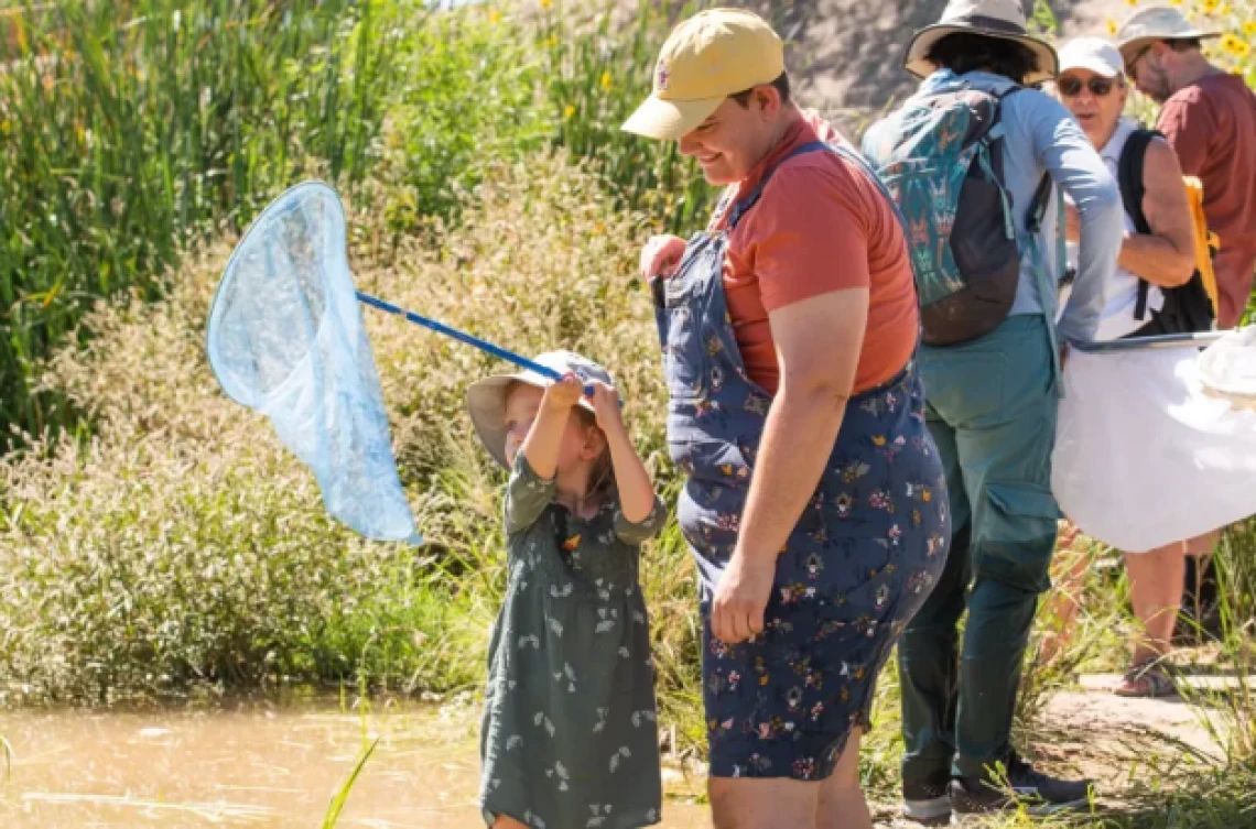 Picture of child holding a dragonfly net with other adults watching at the Santa Cruz River