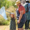 Picture of child holding a dragonfly net with other adults watching at the Santa Cruz River